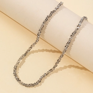 Minimalist smoky grey faceted beaded necklace wrapped on a beige pillar stand