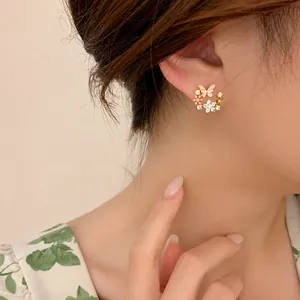 Détail des boucles d'oreilles fleurs et papillons avec moissanite sur un modèle