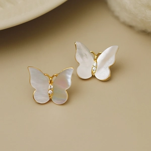 Détail de boucles d'oreilles papillon dorées avec nacre blanche et zircons brillants