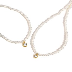 Detail of vintage gold pearl necklace featuring round and heart-shaped gemstone pendants