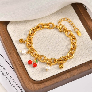 Dettaglio del bracciale dorato in acciaio inossidabile con ciliegie e perle