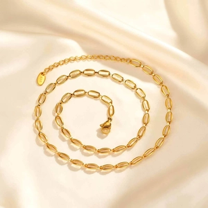 Dettaglio della collana a maglie dorate con targhetta K18 su seta color crema