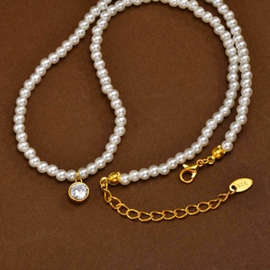 Detail of gold lobster clasp and K18 hallmark on a vintage pearl necklace with zircon