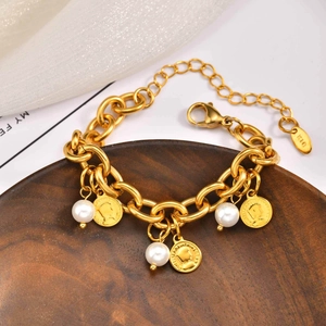 Dettaglio di un bracciale dorato a catena grossa con ciondoli a moneta, perle e incisione K10