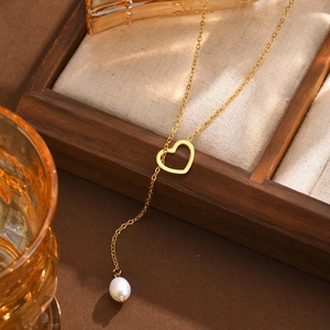 Elegant gold stainless steel heart necklace with a dangling freshwater pearl on wood