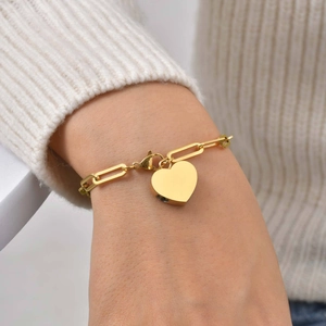 Goldenes Büroklammer-Armband mit poliertem Herzanhänger an einem weiblichen Handgelenk