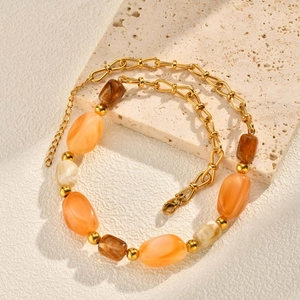 Detail of beaded necklace with gold chain and asymmetrical resin stones on travertine stone
