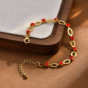 Detailed close-up of gold plated stainless steel bracelet with red crystal rhinestones