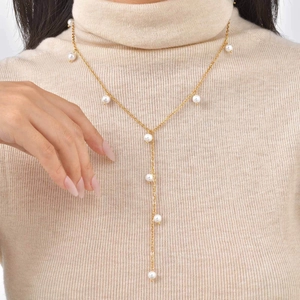 Golden Y-shaped long necklace with white pearls over a beige winter sweater