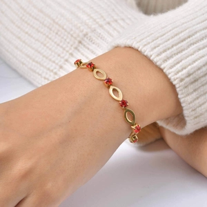 Gold-plated hollow oval link bracelet with red rhinestones on a woman's wrist
