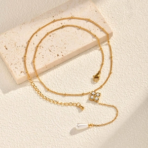 Vue macro du collier en Y trèfle doré serti de zircons avec un détail de perle poire blanche