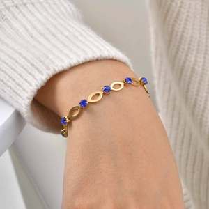 Close-up of gold hollow oval link bracelet with deep blue crystal on a model wrist