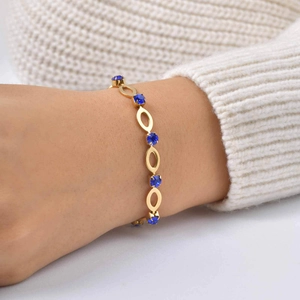 Detail view of gold-plated stainless steel chain with blue rhinestones on a wrist