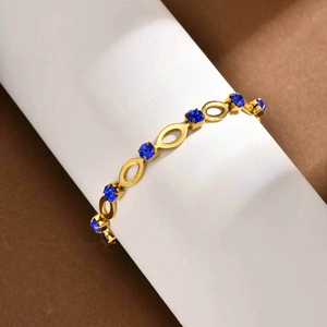 Detail of gold hollow oval link bracelet featuring sapphire blue rhinestone insets
