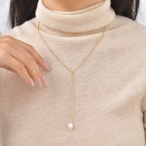 Detail of 18K gold stainless steel Y-shaped necklace with pearl pendant on knit sweater