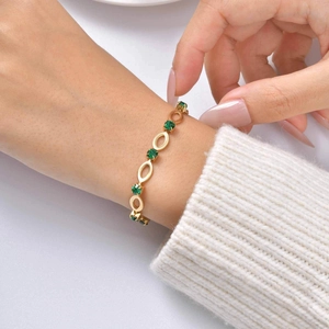 Close-up of gold plated stainless steel bracelet with green zircon oval links on wrist