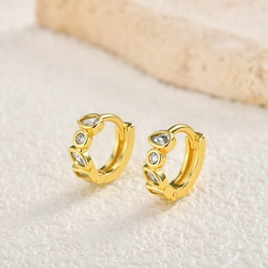 Detail of gold-plated hoop earrings featuring drop-shaped and round-cut cubic zirconia