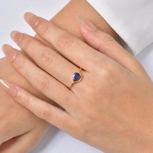Close-up of a gold-plated stainless steel ring with a pear-shaped blue zircon on hand.