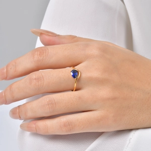 Close-up of a pear-shaped blue sapphire gemstone set on a curved gold band
