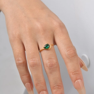 Detailed view of teardrop green zircon ring with golden wavy band on model's hand