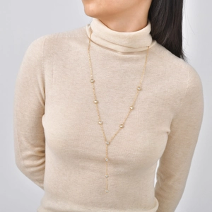 Elegante collana a Y placcata in oro con zirconi circolari indossata su maglione beige