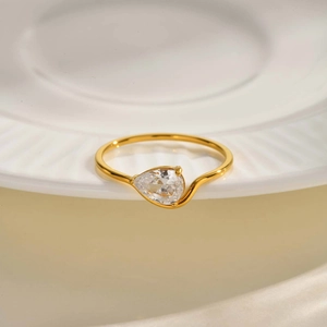 Detailed macro view of teardrop clear zircon gold plated stainless steel ring on plate