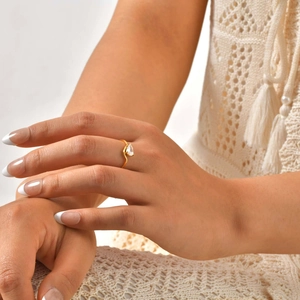 Detail view of gold-plated stainless steel ring with a pear-cut white zircon on model
