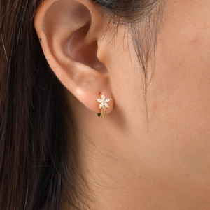 Gros plan d'une créole fleur en or avec pétales en zircon portée par un mannequin