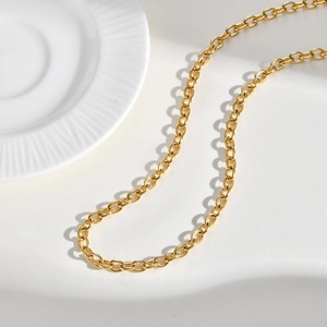 Detail of a golden O-link chain necklace with smooth polished surface on white ceramic