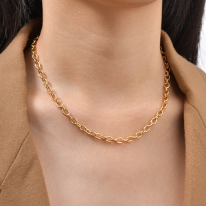 Detail of a minimalist gold oval link chain necklace worn by a model in a brown blazer
