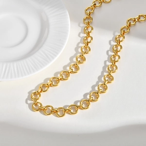 Close-up of polished gold-colored stainless steel circular link chain on a white tray