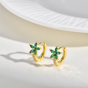 Détail de boucles d'oreilles fleuries dorées avec pierres vertes marquise et pavé de zircons