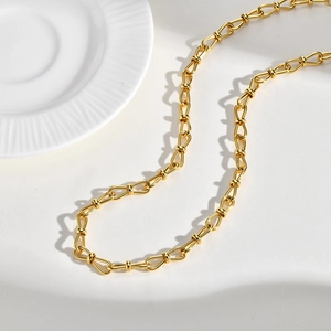 Detailed close-up of golden U-link chain necklace with oval links on white textured background
