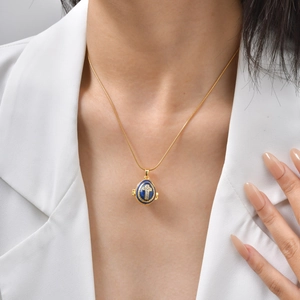 Gros plan d'un pendentif œuf en émail bleu avec croix sur une chaîne dorée
