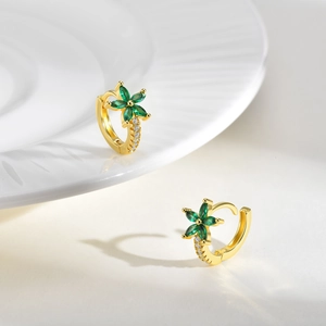 Détail macro de boucles d'oreilles créoles fleurs dorées avec zircons verts marquise