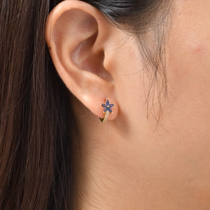 Gros plan d'une boucle d'oreille fleur en or avec cristaux bleus et petits diamants