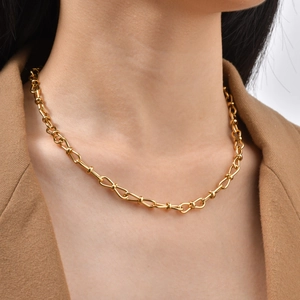 Detail of gold stainless steel link necklace with knotted chain design on model