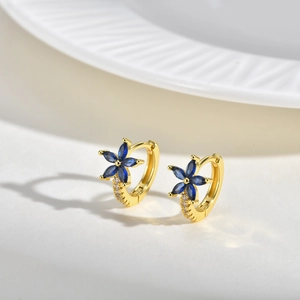 Gros plan de créoles dorées avec fleurs en cristal bleu et pavage de zircons