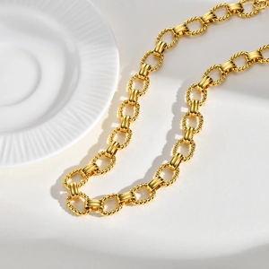 Detailed shot of golden twisted chain necklace with smooth links on white ceramic background