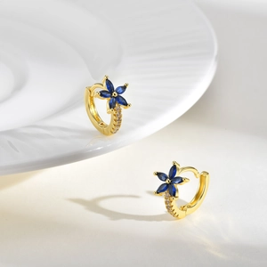 Détail de boucles d'oreilles fleurs dorées avec pétales en zircon bleu et cristaux