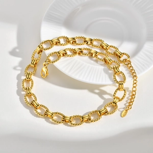Detail of gold necklace showing textured round links and K18 tag with lobster clasp