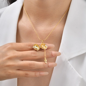 Collier avec pendentif œuf à croix dorée et zircons violets porté par un mannequin