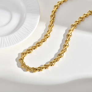 Detailed macro view of golden stainless steel necklace with geometric interwoven chain links