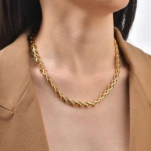 Detail view of a gold-plated interlocking cable chain necklace worn with a blazer