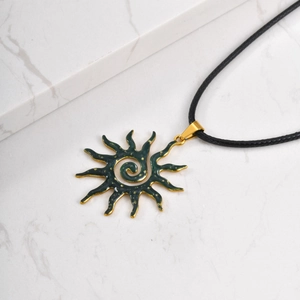 Detalle de colgante de sol vintage con esmalte verde y cordón trenzado negro
