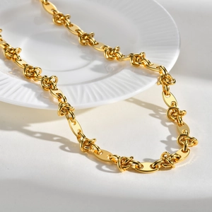 Detail of gold chunky chain necklace with textured knot links and flat oval rings