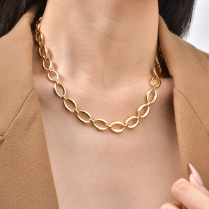 Detailed view of polished gold oval link chain necklace worn with casual blazer