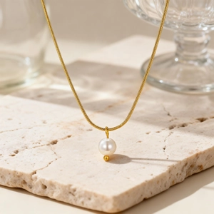 Elegante collana a catena serpente dorata con perla tonda su superficie in pietra