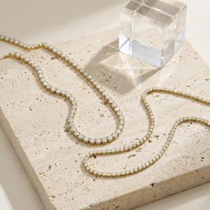 Elegante goldene Tenniskette mit runden Zirkonia-Steinen auf minimalistischem Stein