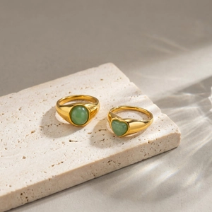 Dettaglio di anelli dorati vintage con pietre di avventurina verde a cuore e ovali